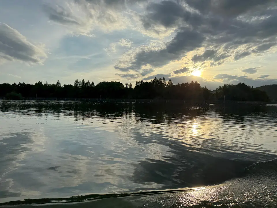 Atardecer sobre el lago Xiazhu: las aguas calmas reflejan un cielo dramático mientras el sol se esconde tras la vegetación, en uno de los rincones más serenos del sur de China.