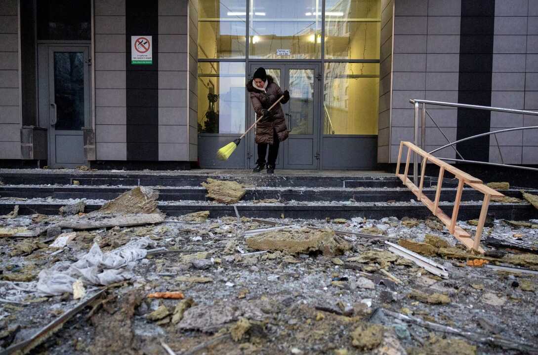 Una mujer retira escombros de la entrada de un edificio atacado en Kiev, este martes.Thomas Peter (REUTERS)